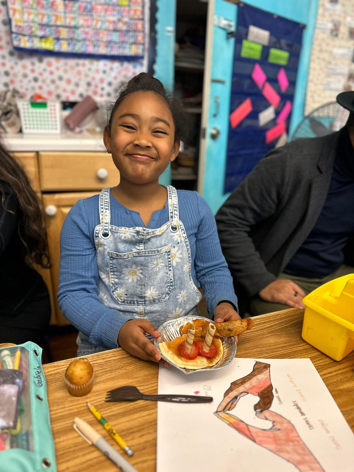 A student smiling while holding a breakfast plate she decorated in class